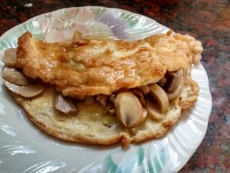 omelette de champiñones individual, color amarillo por el huevo combinado con el color de los champiñones, presentado con el relleno casi a la vista